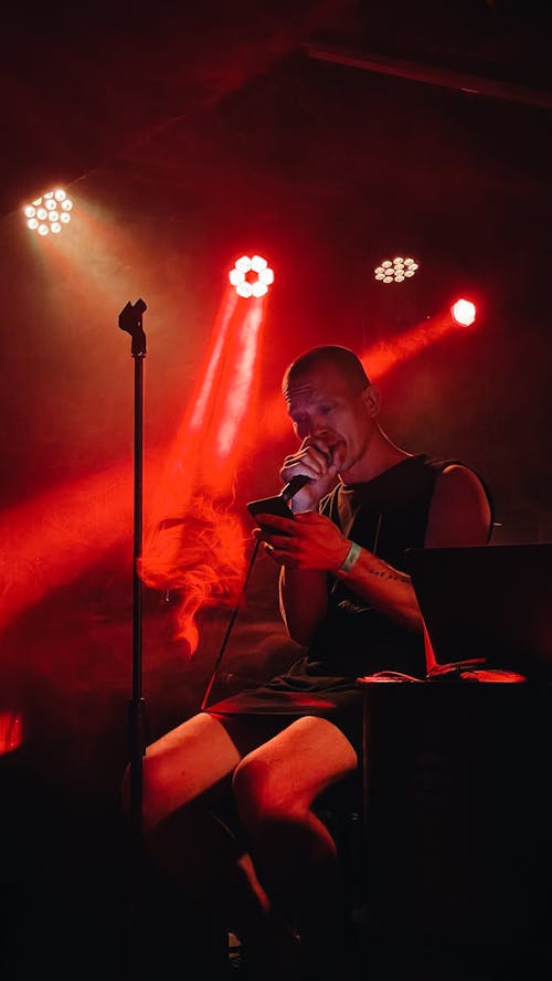 A Man Using His Smartphone while Holding a Microphone