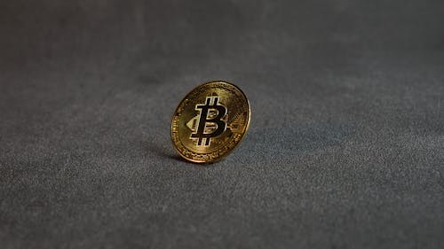 A Golden Bitcoin on a Grey Surface