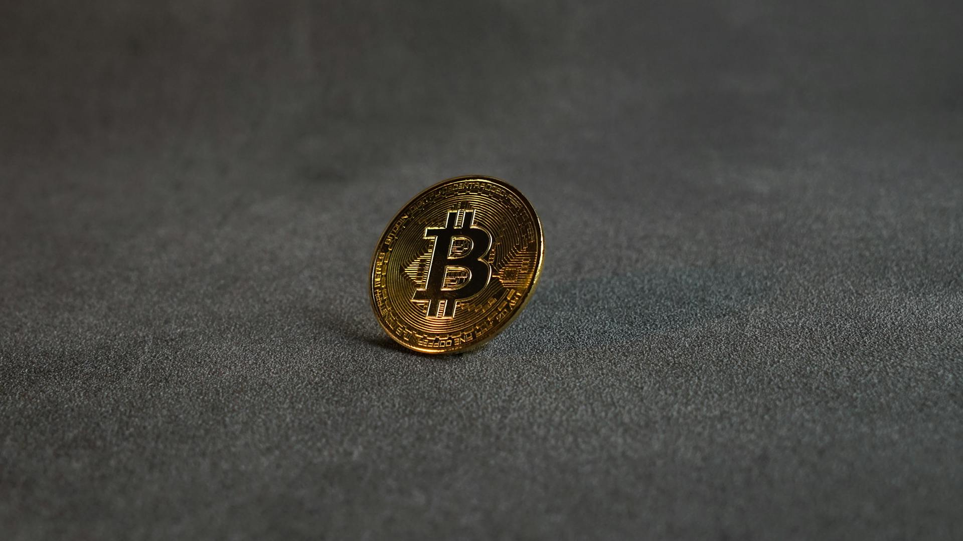 A Golden Bitcoin on a Grey Surface