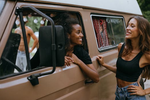 Two friends share a happy moment by their camper van during a road trip adventure.