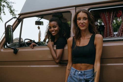 Free Smiling friends enjoying a summer road trip in a classic van. Outdoor adventure awaits. Stock Photo
