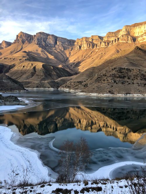 Free Stunning reflection of rugged mountains in a serene Russian lake during winter. Stock Photo