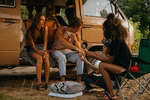 Free A group of friends enjoying a camping trip with a camper van, embodying diversity and fun in the outdoors. Stock Photo