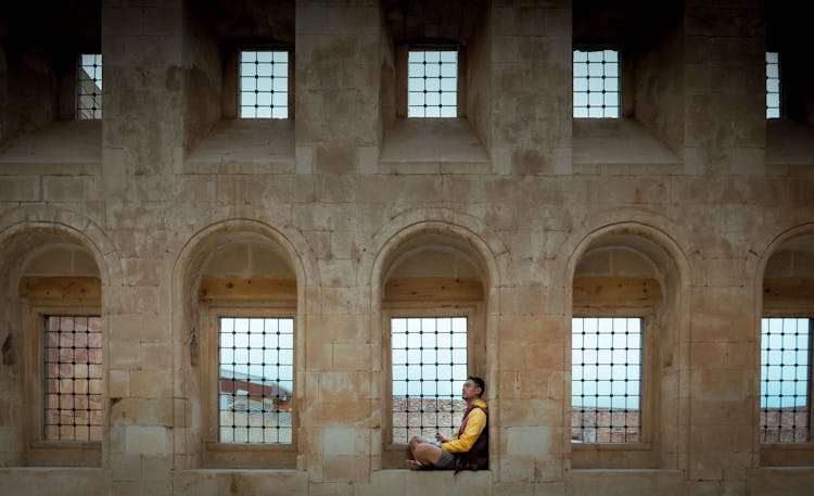 Man Sitting On A Window Ledge