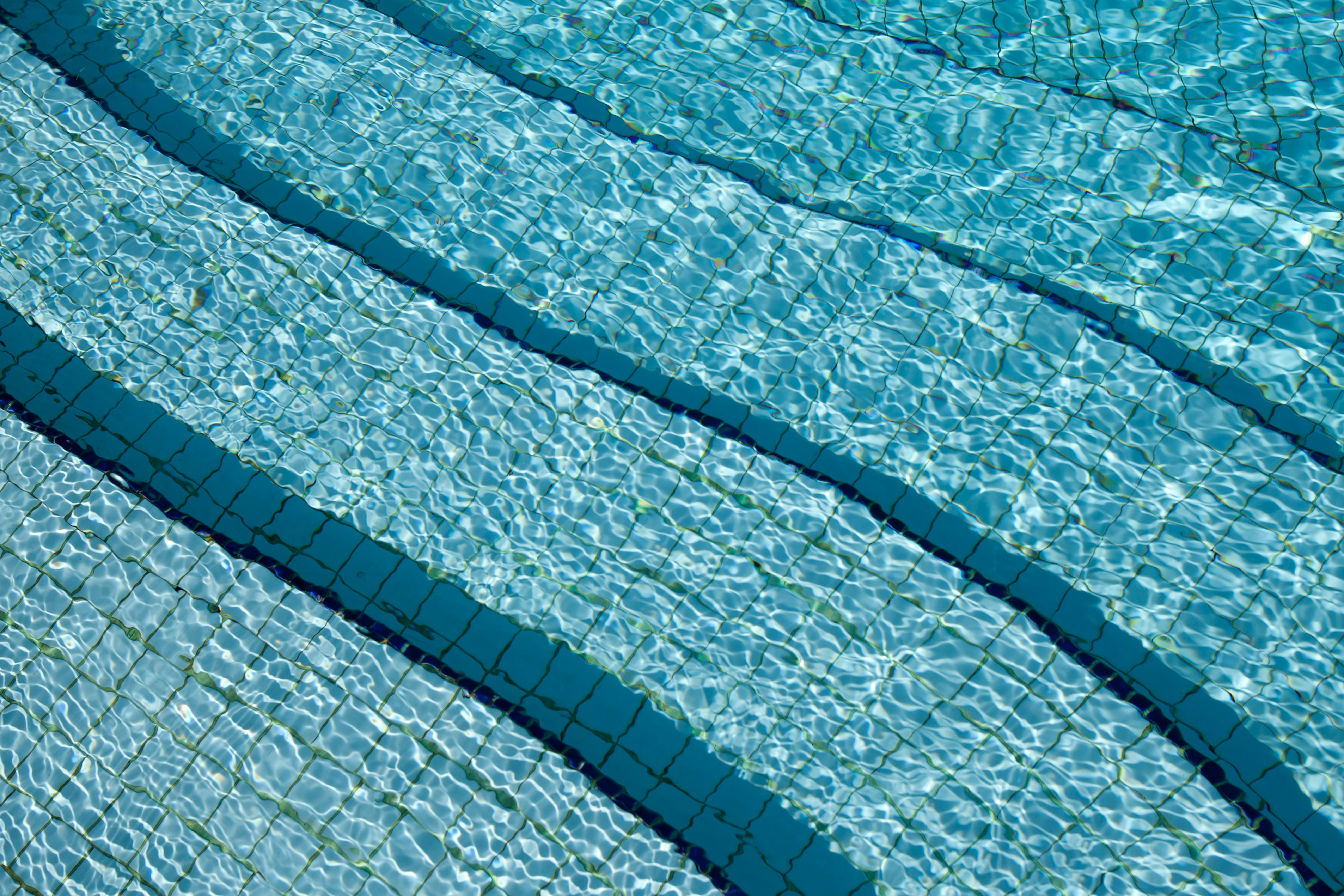 A detailed view of crystal clear swimming pool water over a tiled surface, showcasing its calm and refreshing nature.