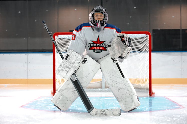 A Goaltender In Front Of A Goal In A Hockey Rink