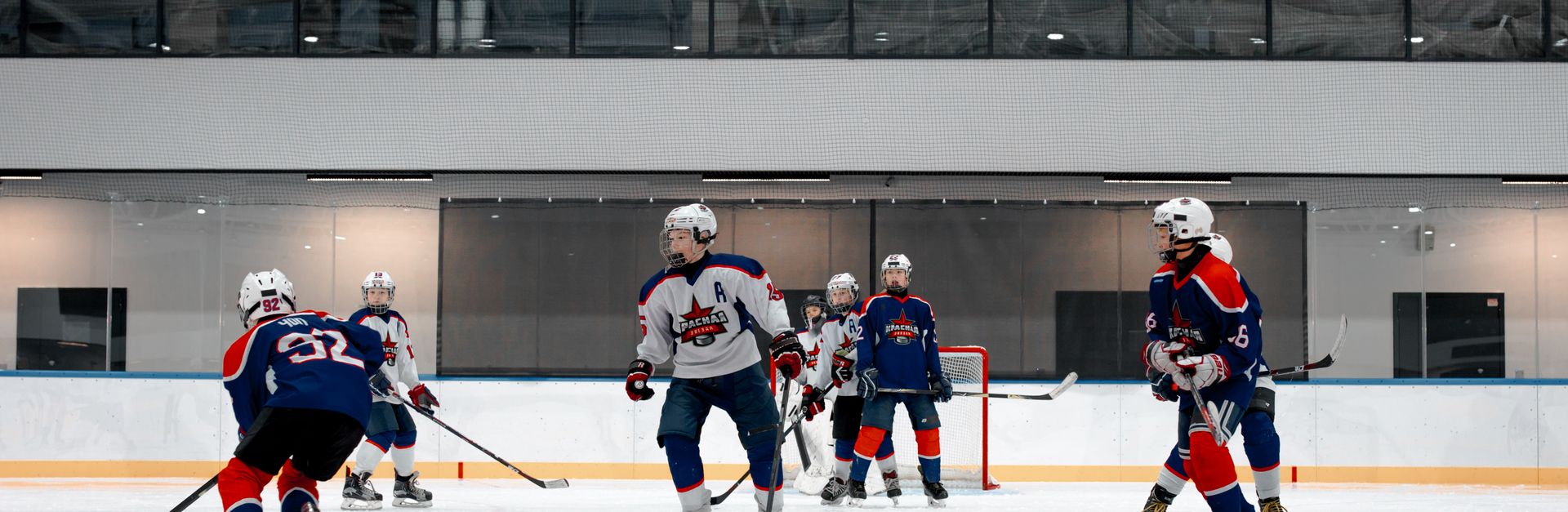 Competitive ice hockey game with athletes in blue and red uniforms on an indoor rink.
