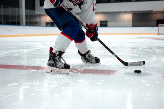 Focused ice hockey player on rink with puck and stick, showcasing agility and sports gear.