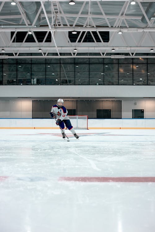 A Hockey Player Skating on Ice Rink