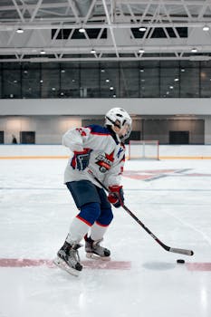 A young hockey player in full gear playing on an indoor ice rink. Dynamic action shot.