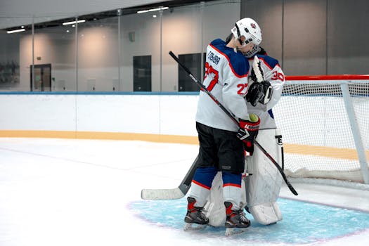 Two ice hockey players hugging on the rink, symbolizing sportsmanship and teamwork.