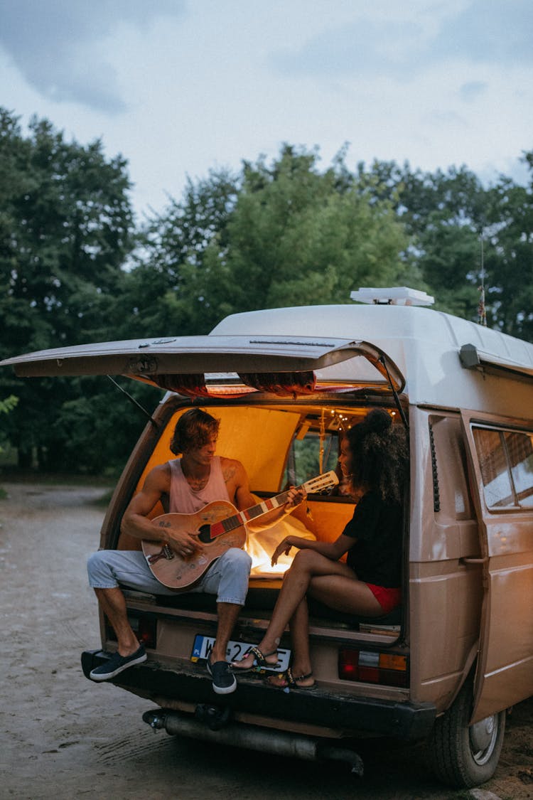 Friends Sitting At The Back Of A Camper Van