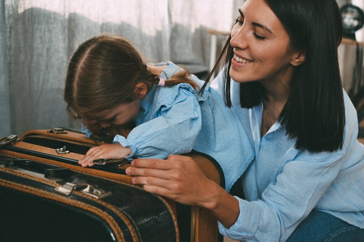 Woman And Daughter Packing Suitcase Together