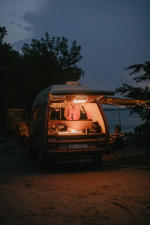 Person Sitting Near a Parked Camper Van