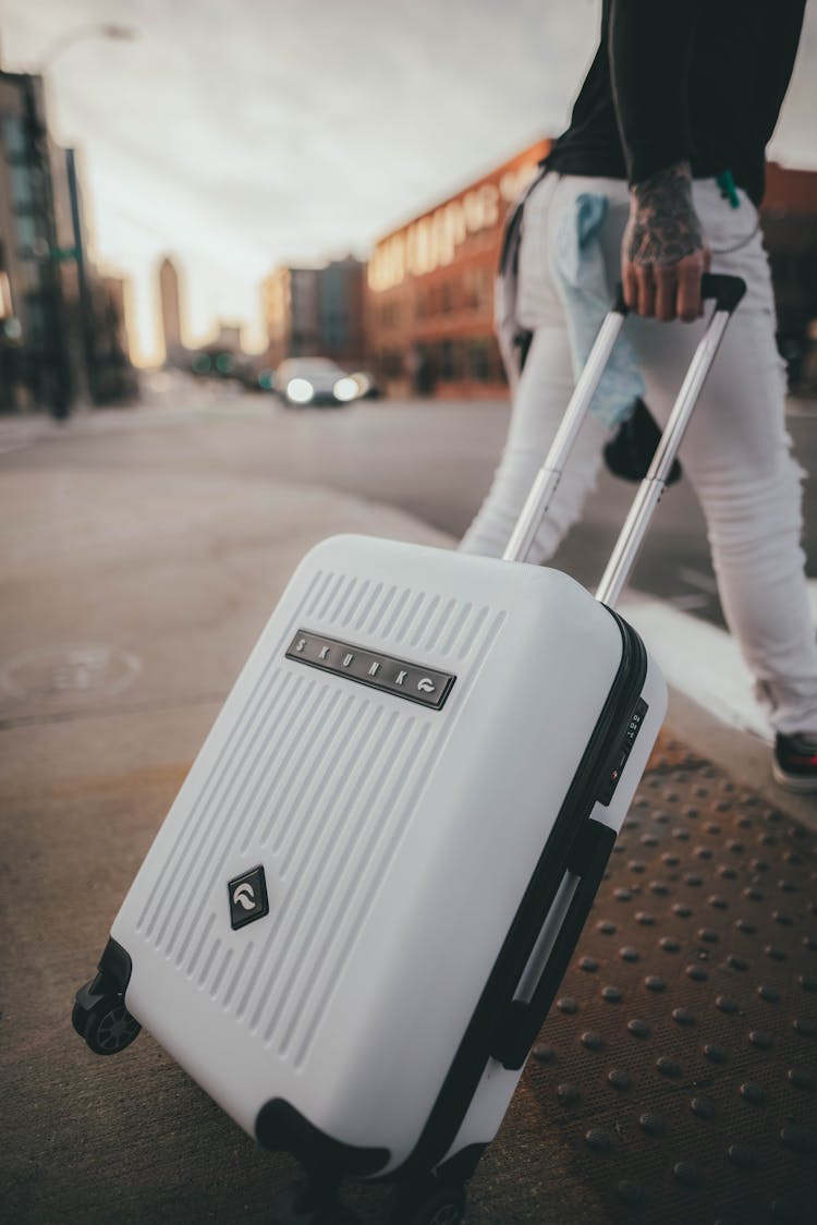 Person Walking While Pulling The White Luggage 