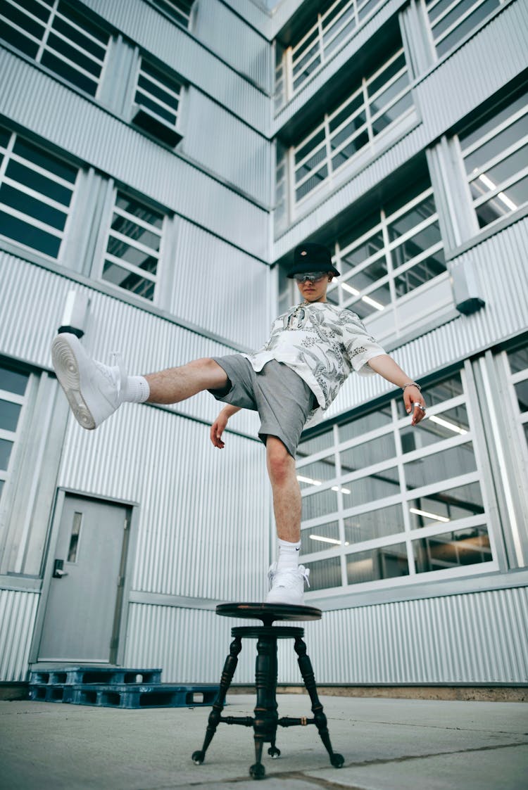 Man Standing On One Leg On Stool Chair