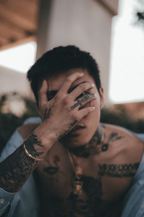 Free Tattooed adult male with hand on head creating a moody, stylish portrait. Stock Photo