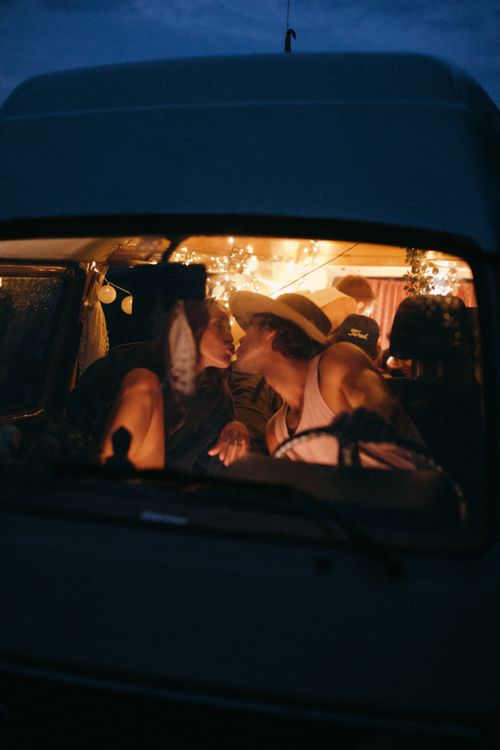 Free Couple shares a tender kiss in a cozy camper van under warm lights. Stock Photo