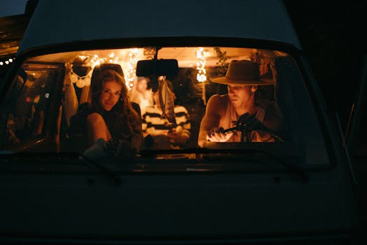 Friends enjoying a cozy night inside a camper van with glowing string lights, embracing wanderlust and travel.