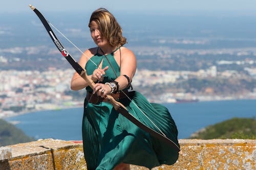 A Woman in Green Dress Holding a Bow and Arrow