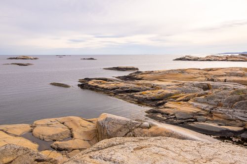 Free A serene rocky seascape with calm ocean water and a cloudy sky, perfect for nature lovers. Stock Photo