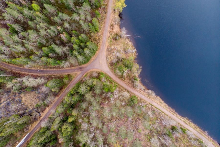 Drone shot of forest crossroads in Nittedal, Norway, beside a serene lake.