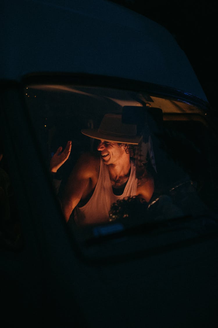 Man In Tank Top Laughing Inside The Car During The Night