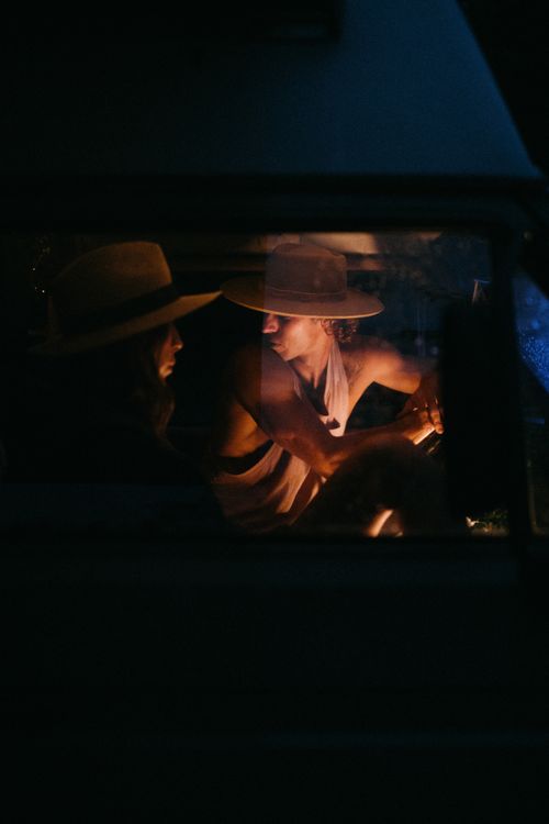 Free Moody nighttime scene of two adults with hats inside a dimly lit car. Stock Photo