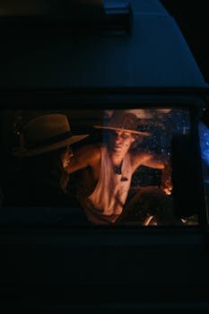 Two people enjoying a serene evening inside a van, illuminated by soft light.