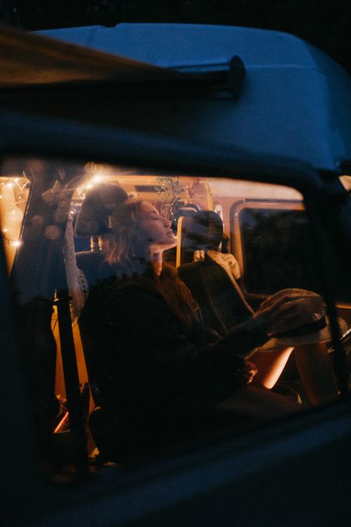 Free Woman relaxing inside a retro camper van during dusk, evoking a warm, serene atmosphere. Stock Photo