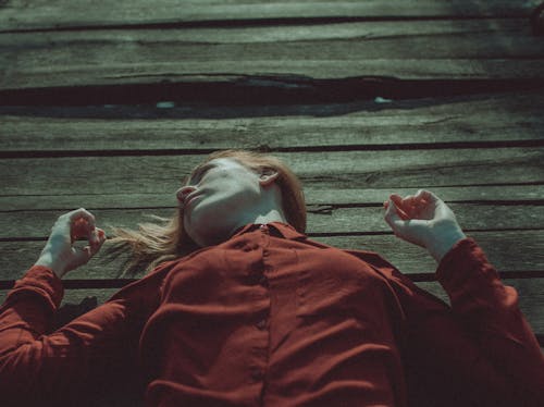 Woman In Red Button-Up Shirt Lying Down On A Wooden Floor