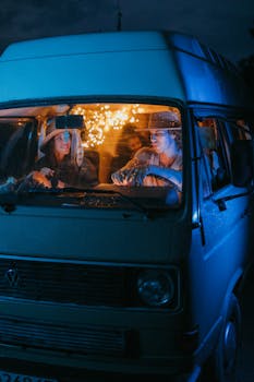 Two adults enjoying a nighttime ride in a vintage Volkswagen van, under a starlit sky.