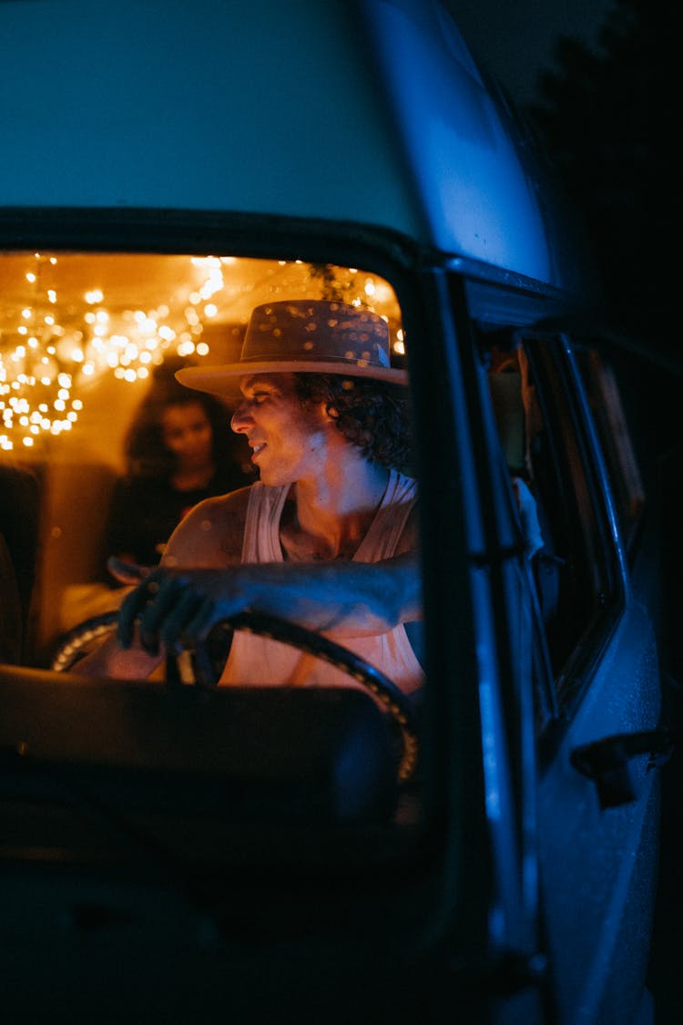 Man In White Tank Top With A Hat Driving A Van