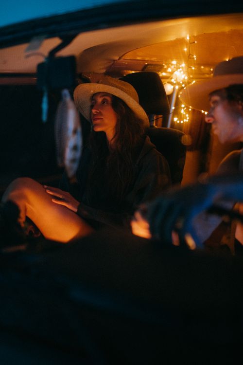 Free Couple enjoying a cozy night drive illuminated by gentle string lights. Stock Photo
