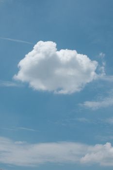 A single puffy cloud floats in a bright blue sky, creating a tranquil scene.