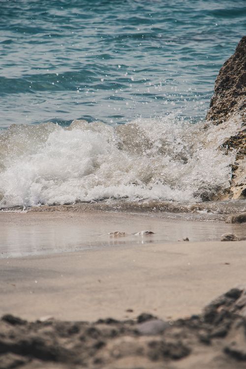 Free Waves crashing on a sandy beach in Almería, Spain, capturing a serene seascape and rocky shore. Stock Photo