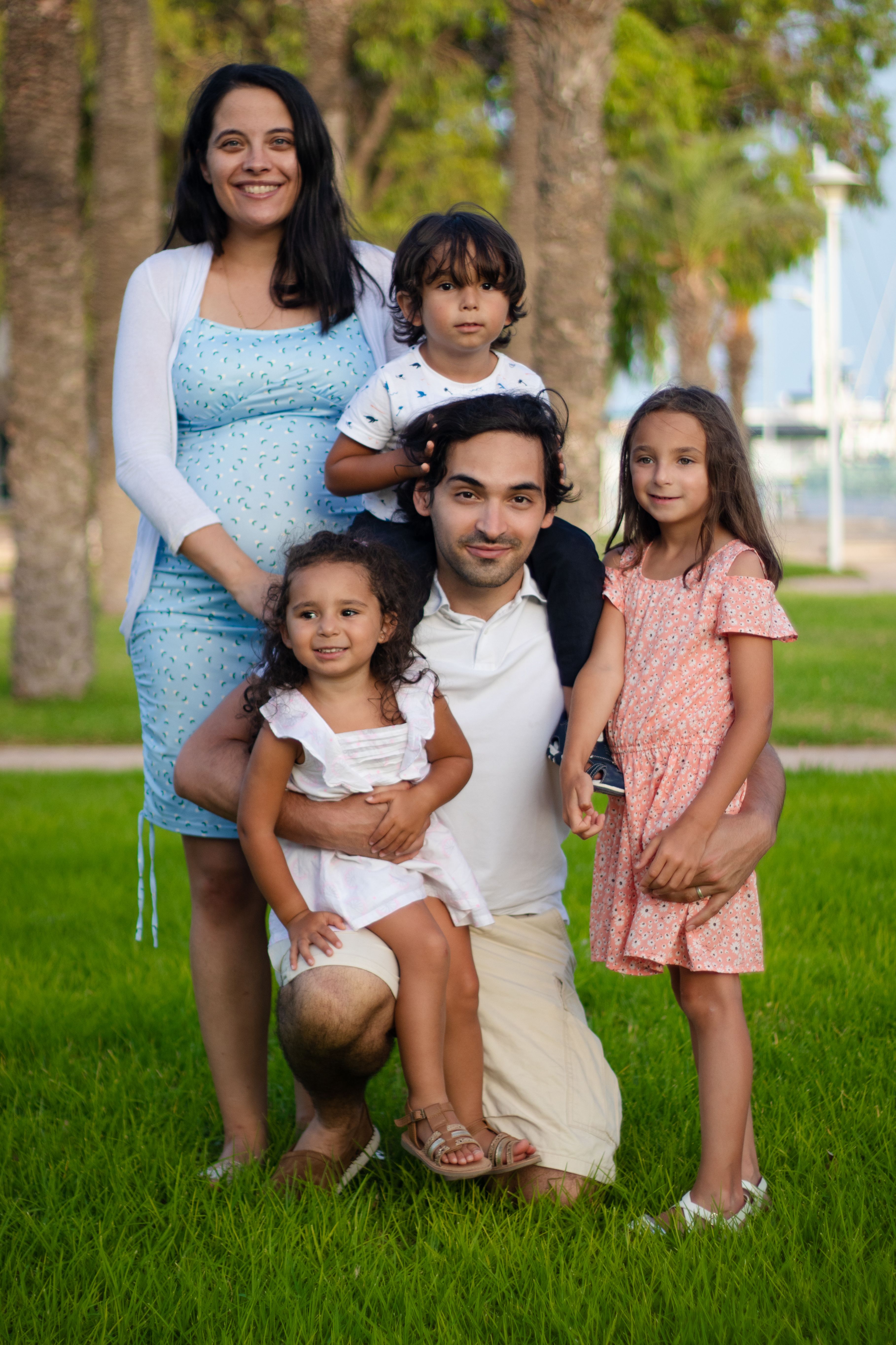 A joyful family captures a moment together in a sunny park setting.