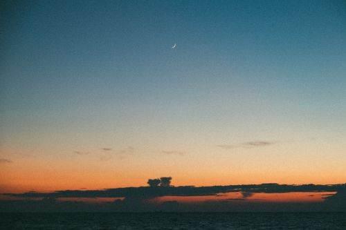 Free A tranquil twilight sky with a crescent moon over a calm ocean, capturing the serene beauty of nature. Stock Photo