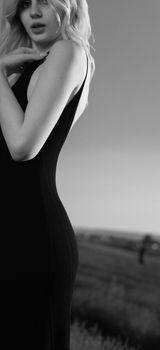 Stylish black and white portrait of a woman in a black dress outdoors.