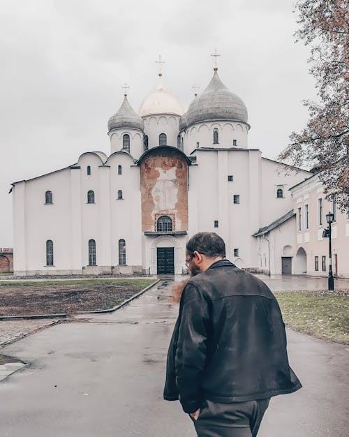 Man in Black Jacket Walking Near a Church