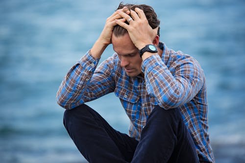 Uomo In Camicia A Quadri Blu E Marrone Che Tocca I Suoi Capelli