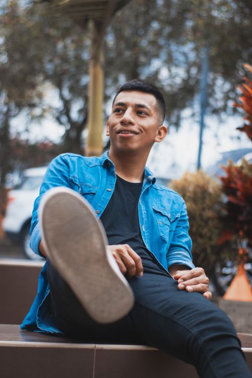 Free A portrait of a smiling man sitting outside in casual attire, expressing leisure and joy. Stock Photo