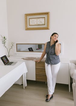 Woman standing in home office making a phone call, engaging in remote work.