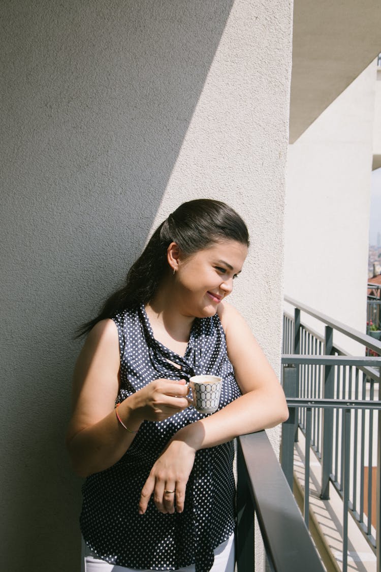 A Smiling Woman On A Balcony Holding A Mug