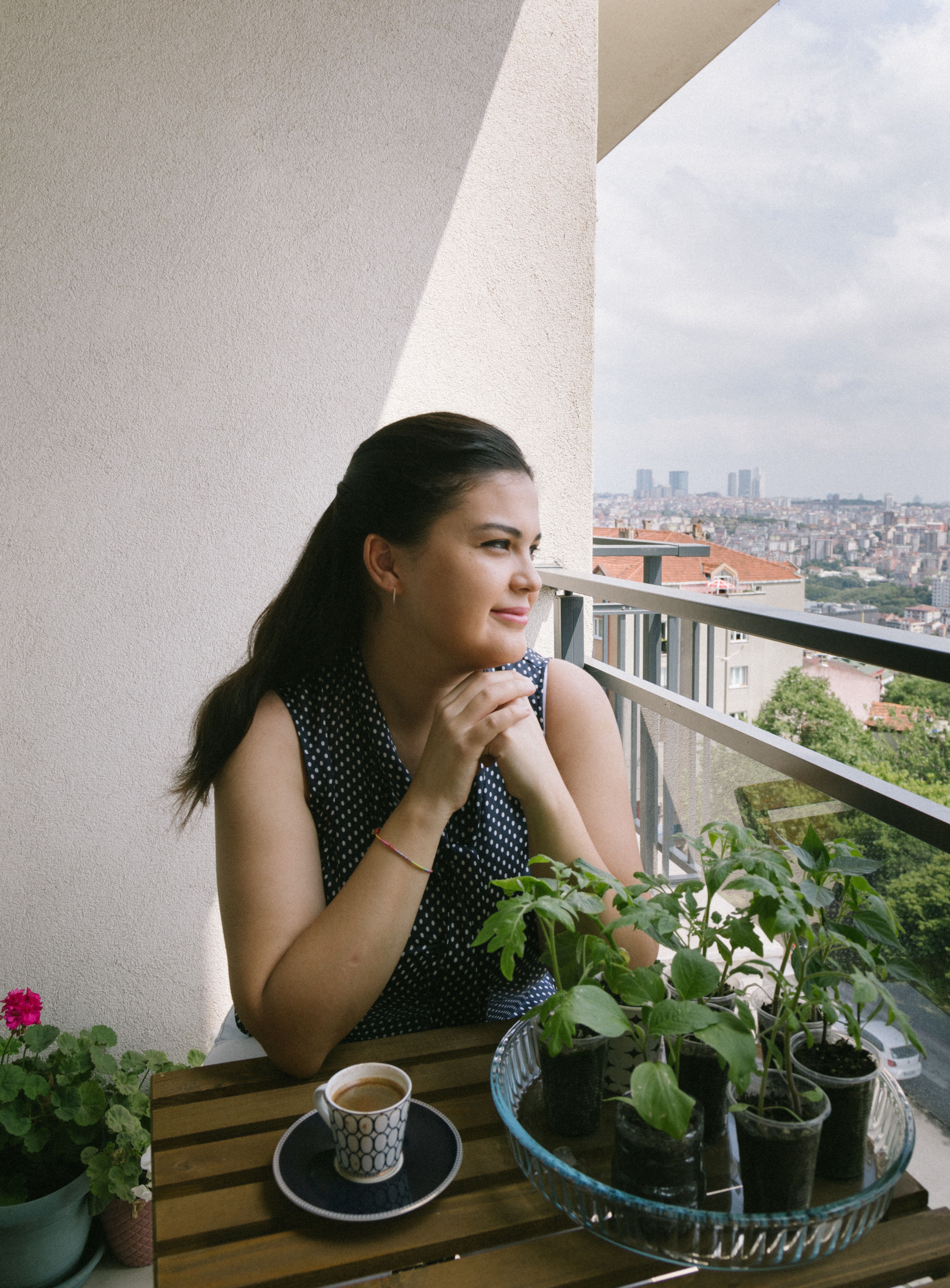 Woman sipping coffee while enjoying the view from an Istanbul balcony.