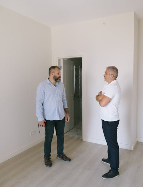 Man in White Shirt Standing beside Man in Blue Long Sleeve Shirt