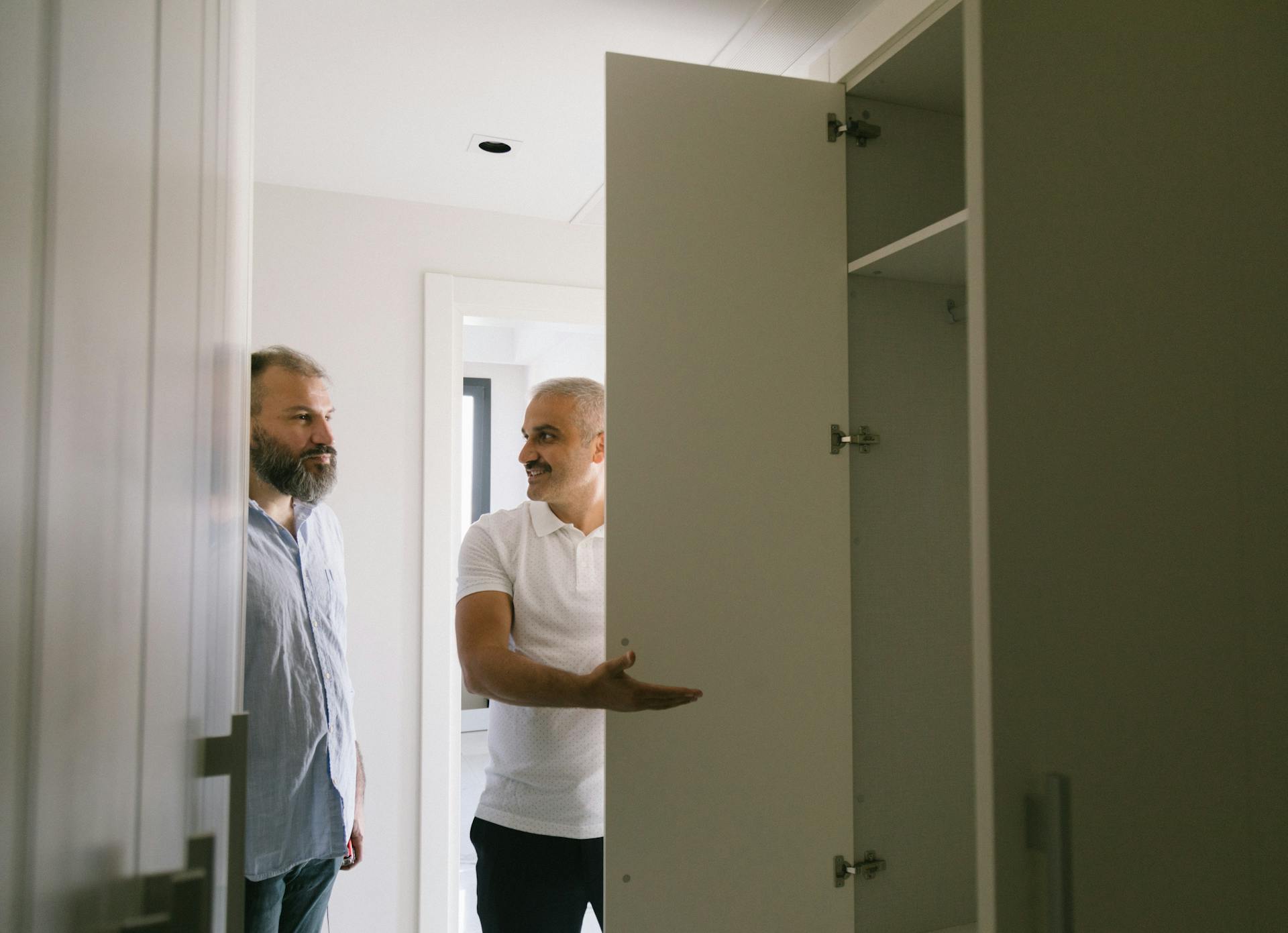 Two men discussing and inspecting a closet in a modern apartment setting in Istanbul.