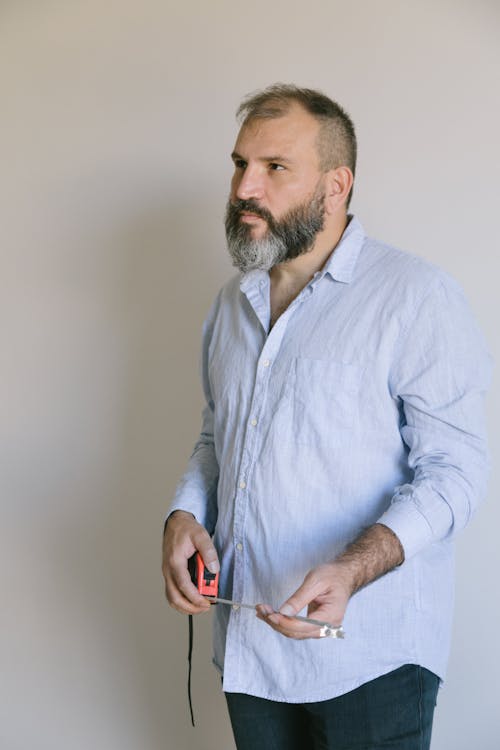 Man in Blue Long Sleeve Shirt Holding Measuring Tape