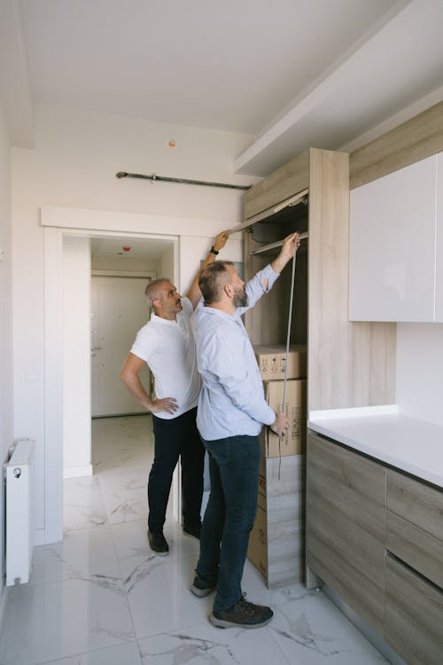Free Man Measuring a Cabinet with Another Man Stock Photo