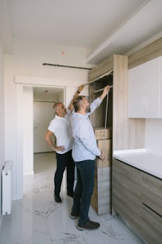 Two men measuring a modern kitchen cabinet for a renovation project in an apartment.